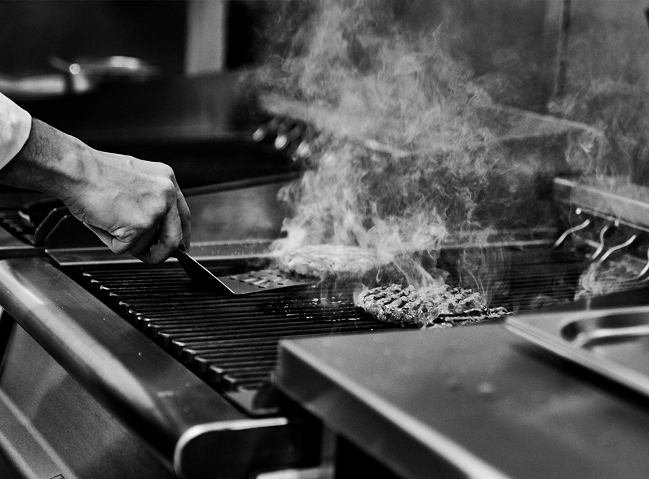 Chef cooking burger patties on grill