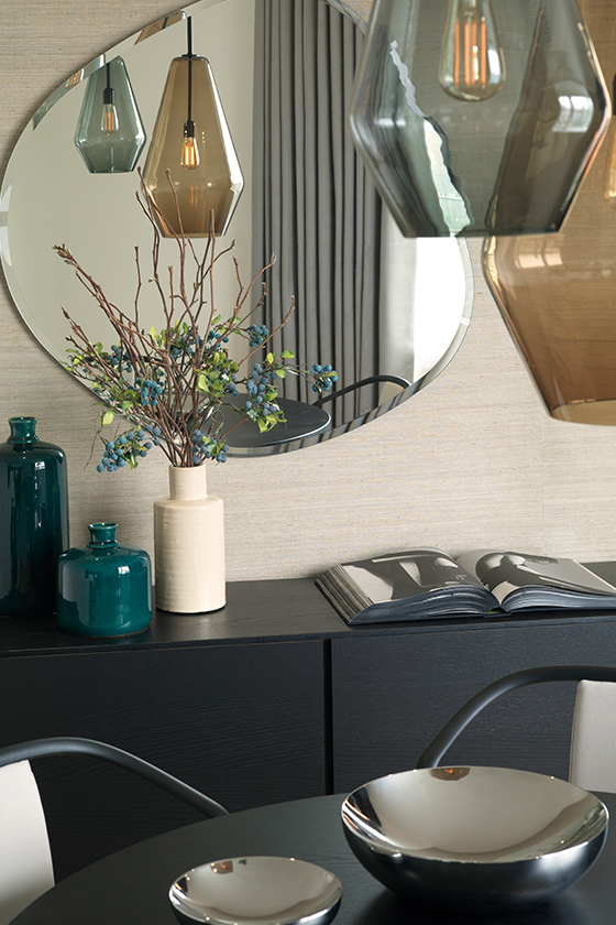 Large glass light fitting hanging from the ceiling reflected in mirror above sideboard