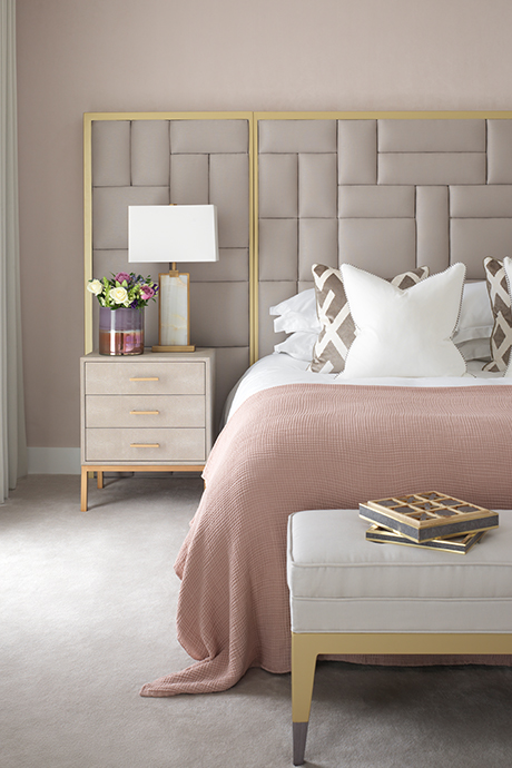 Side table view of the master bedroom with large grey and gold headboard