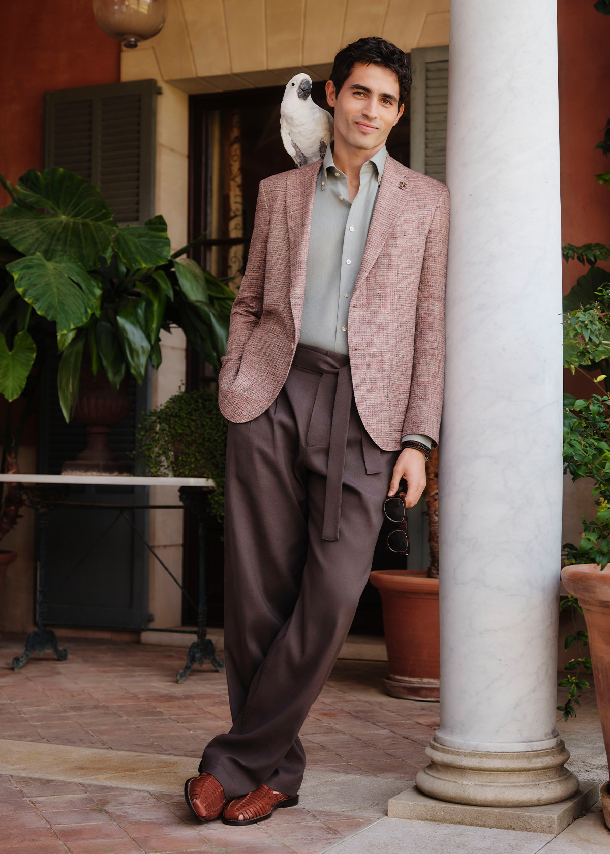 Man wearing salmon pink blazer and mismatched dark tailored trousers