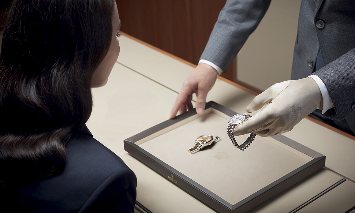 A woman looking at a Rolex watch in a  man's hand