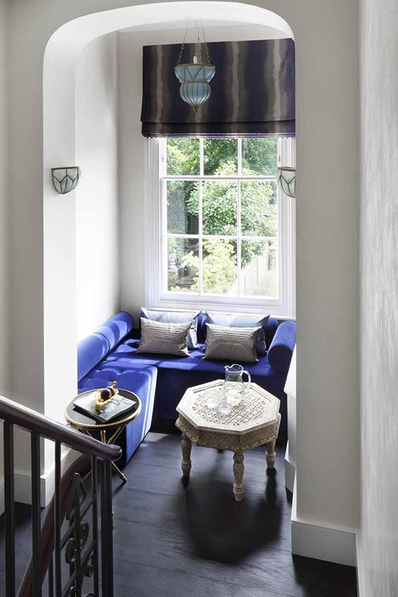 Seating area on landing with bright blue built in sofas and Moroccan style wall lights and tables