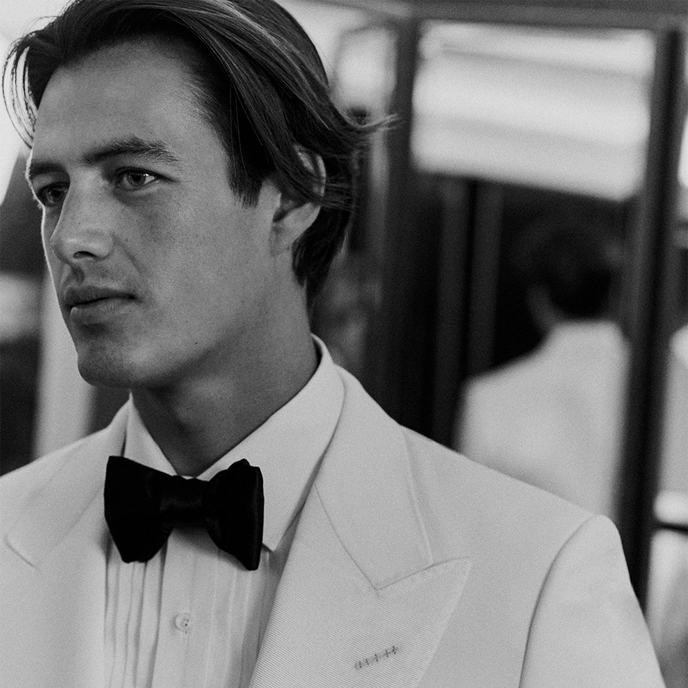 Groom in black tuxedo sitting down