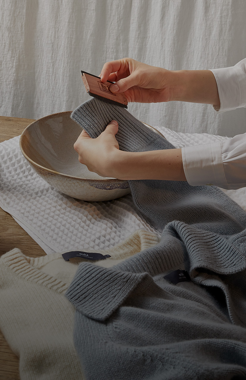 Womans hands washing cashmere with in a scrubber in a bowl of water