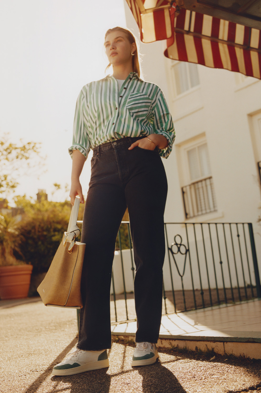 A model stands in a sunny British seaside town and wears Agolde dark grey straight-leg jeans