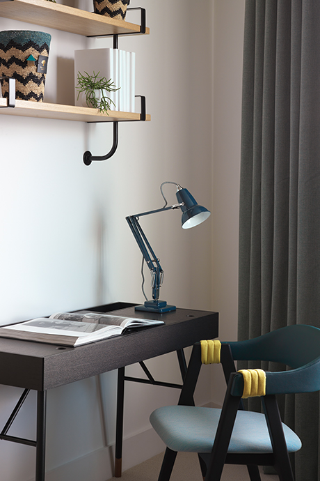 Brown wooden desk with dark green table lamp and chair