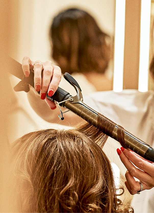 Stylist curling a client's hair