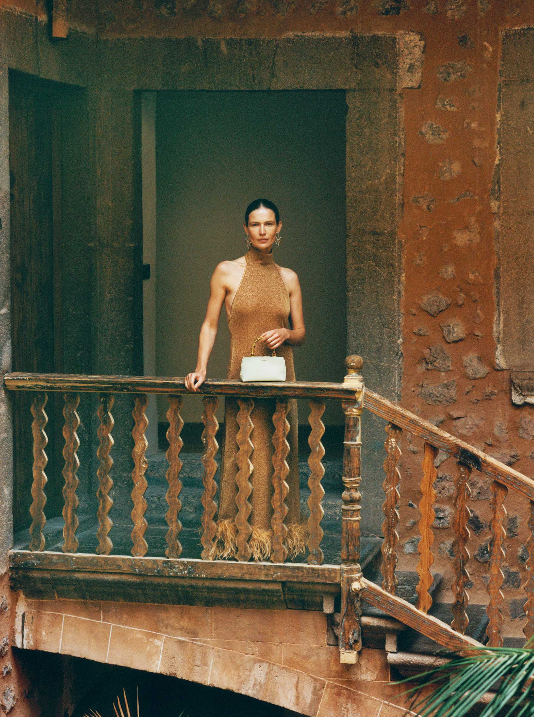 Lady at top of stairs wearing glittery copper halter neck dress