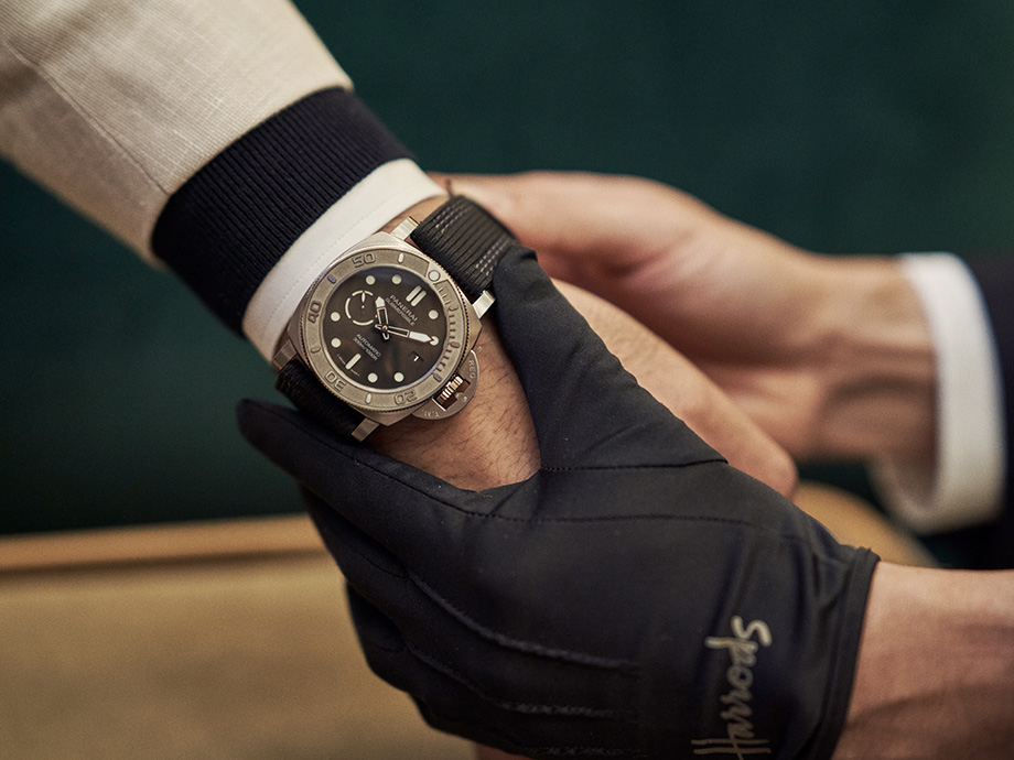 Staff where a Harrods branded glove helping a customer fit a Panerai Submersible