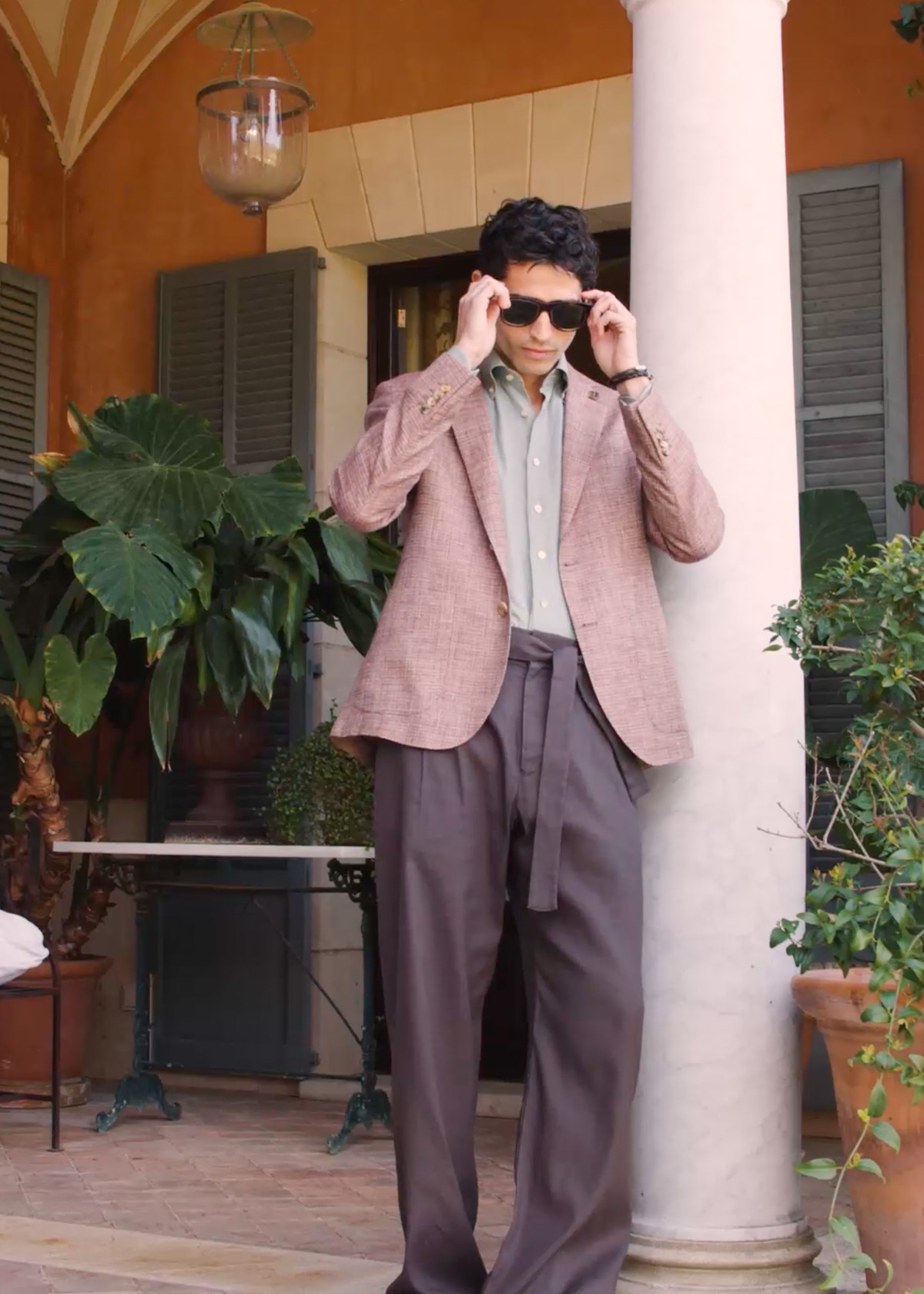 Video of a man wearing salmon pink blazer and mismatched dark tailored trousers