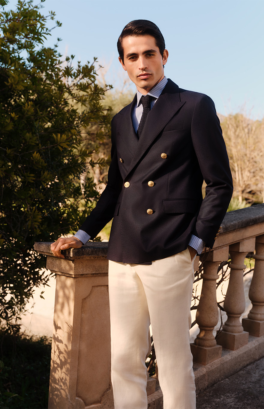 Man wears smart navy blazer in elegant garden surroundings