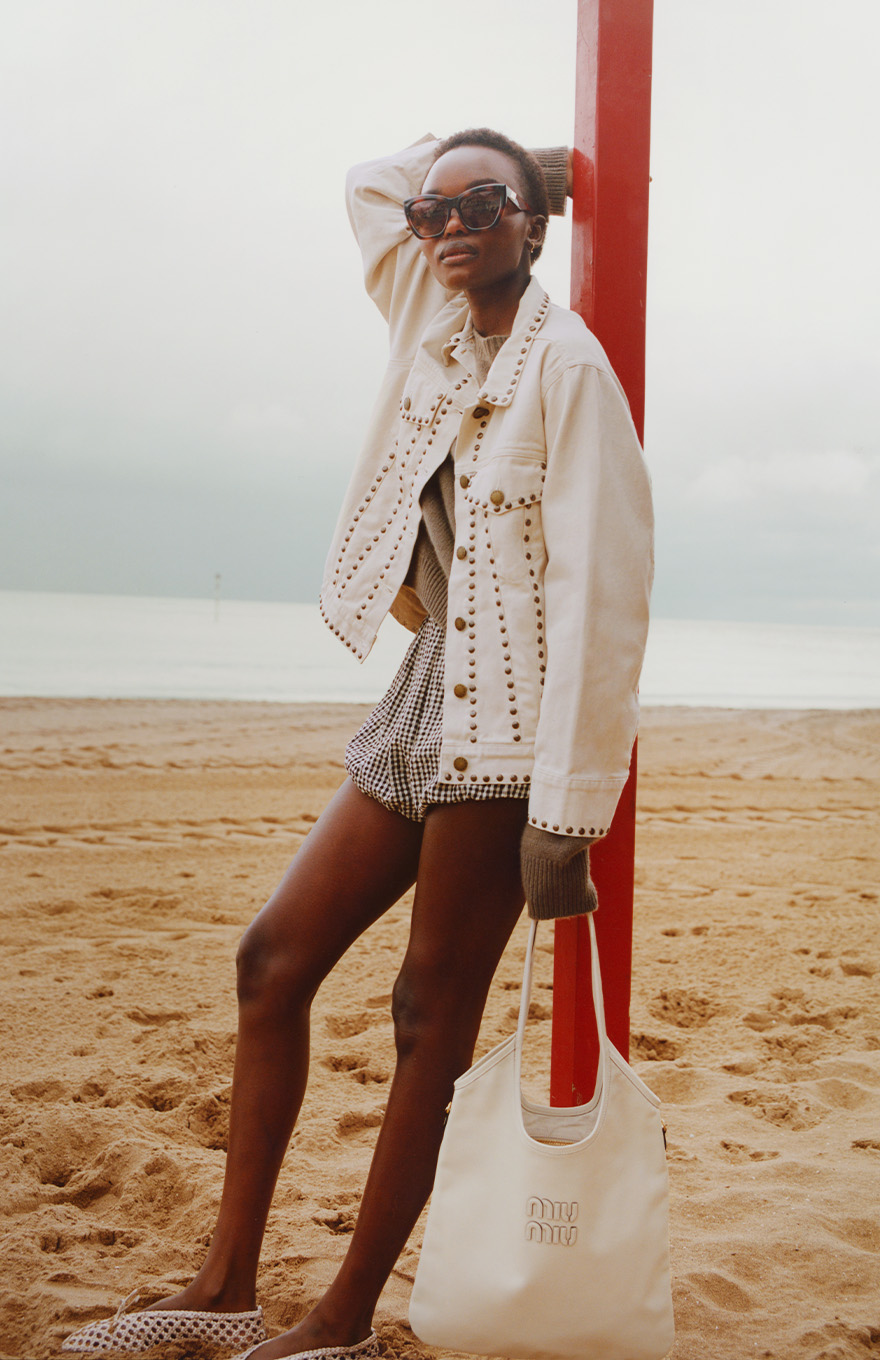 Model stands on beach in British seaside town wearing cream embellished denim