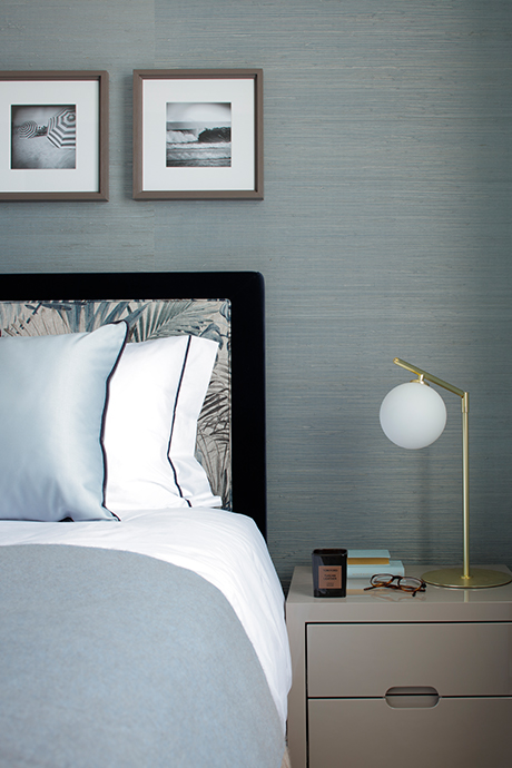 Side table of guest bedroom in blue tones with a white lamp