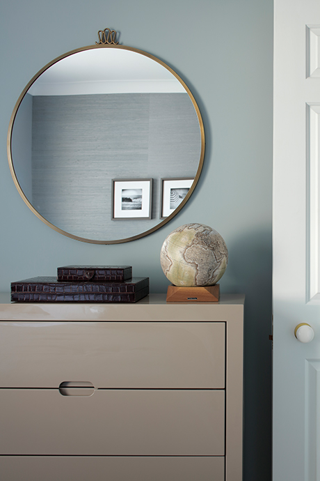 Light brown chest of draws with a gold circular wall mirror above it