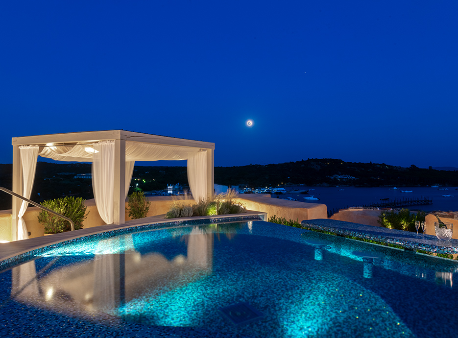 Pool area at night with infinity pool and pergola