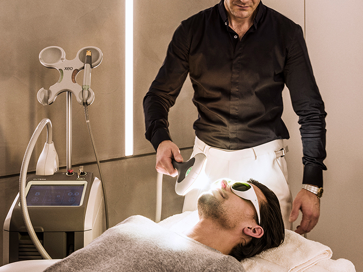 Dr Costas Papageorgiou using an infrared light on a client for face & neck rejuvenation