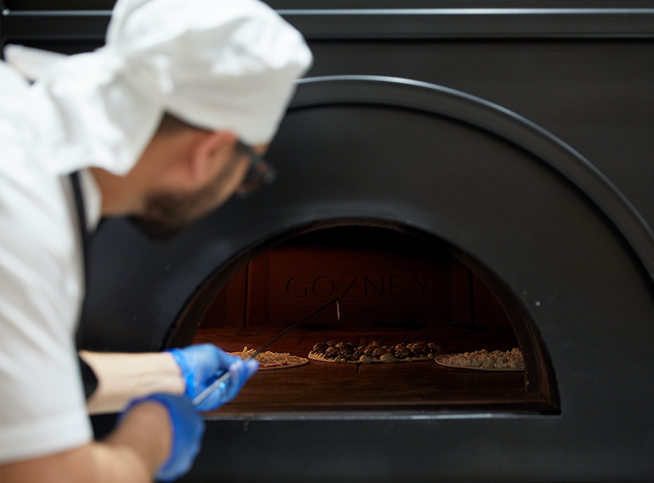 Chef cooking a flatbread in the wood-fired oven