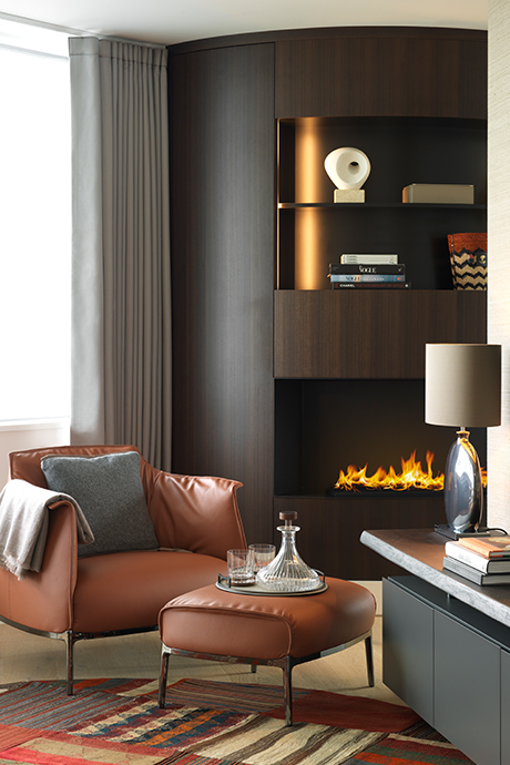 Brown leather chair and footrest in front of large dark wooden fireplace