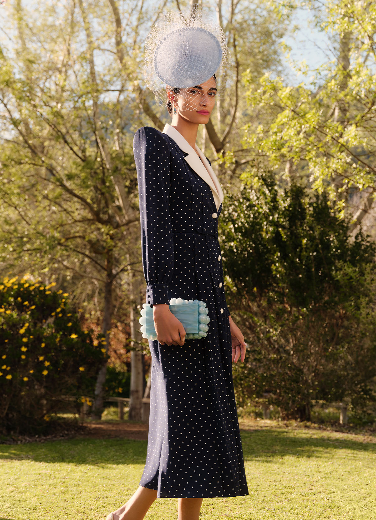 Model wears navy blue and cream polka-dot Alessandra Rich dress and pale blue Rachel Trevor-Morgan fascinator