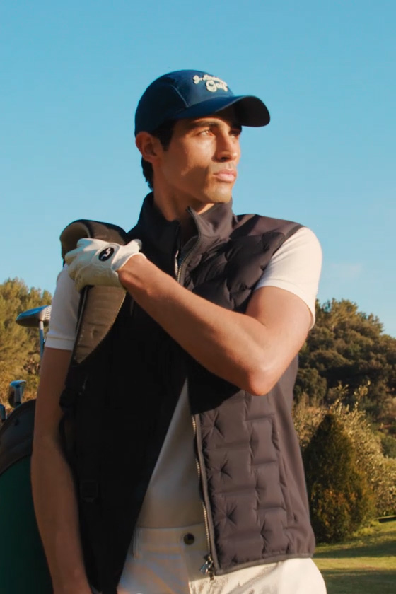 Man plays golf wearing Polo Ralph Lauren polo shirt, Bogner gilet and shorts, J.Lindeberg cap and gloves