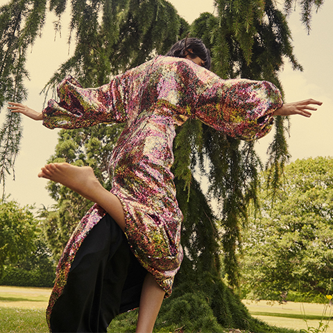 Woman in pink long sequin dress jumping in the air