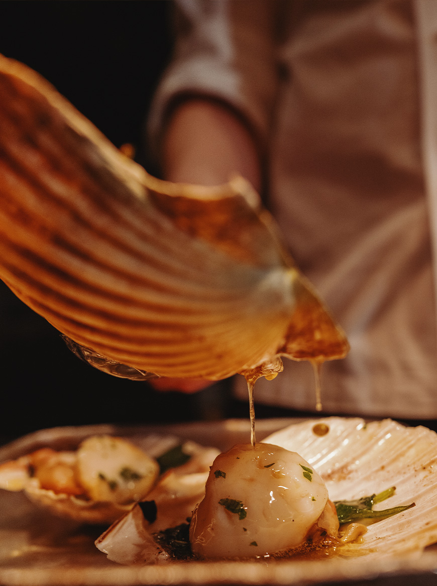 Tom Kerridge sprinkling sea salt on chips and a bowl of chips with lobster on top