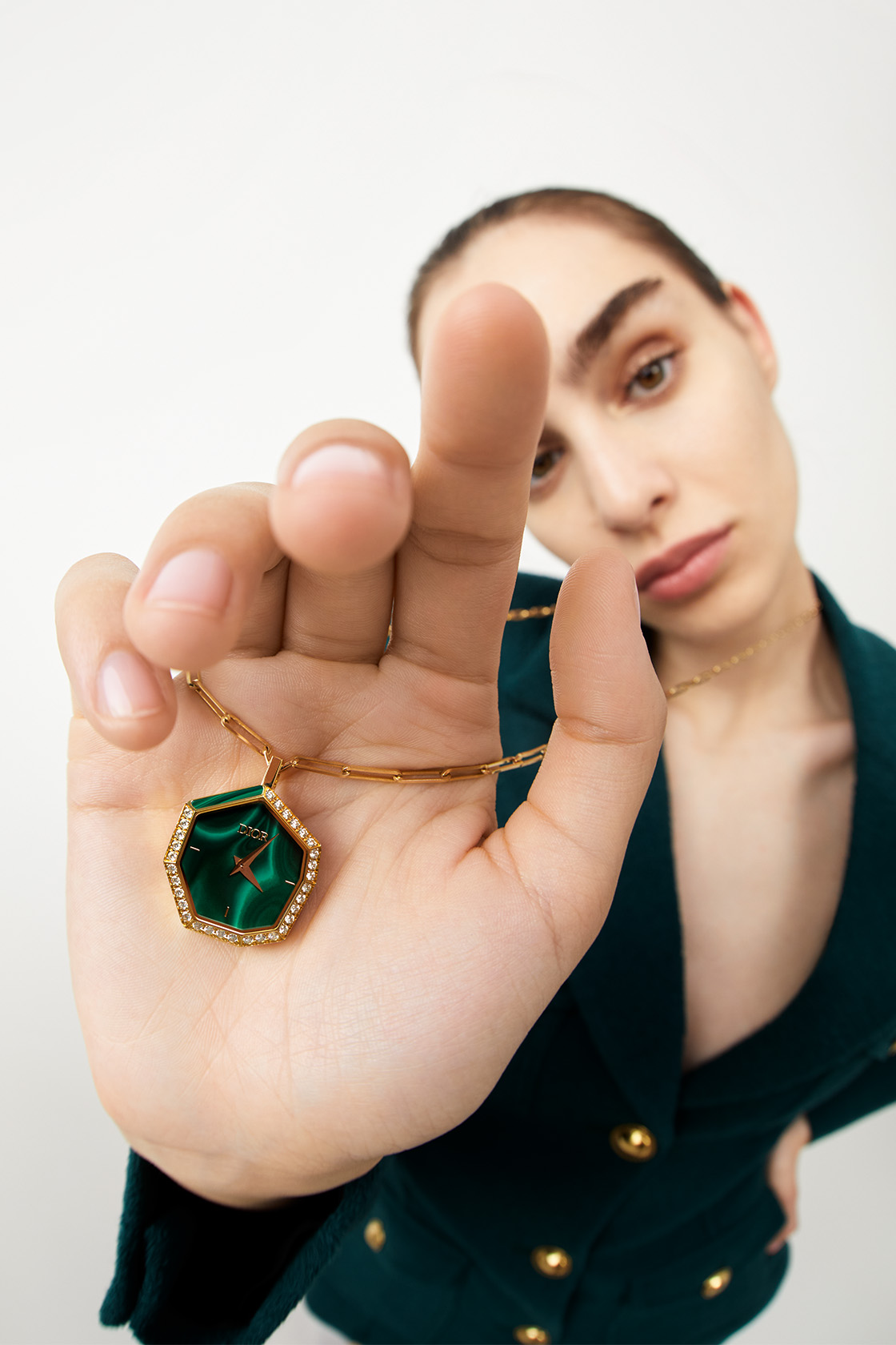 Model wearing holding a green Dior fine watch necklace