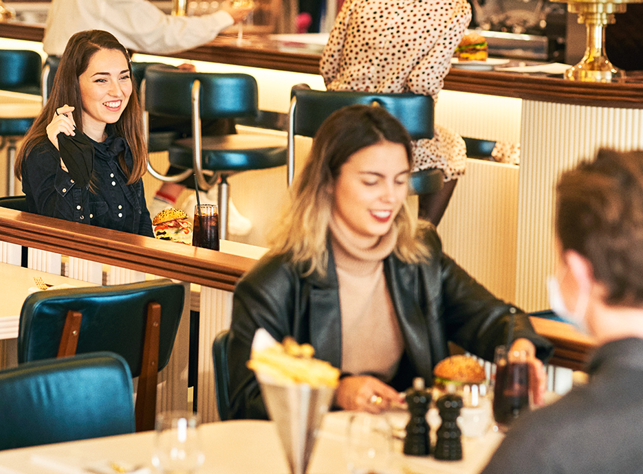 People enjoying burgers and chips in the restaurant seating area