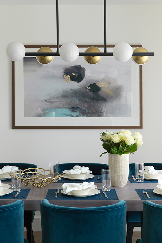 White and gold chandelier above dining room table with abstract painting on the wall