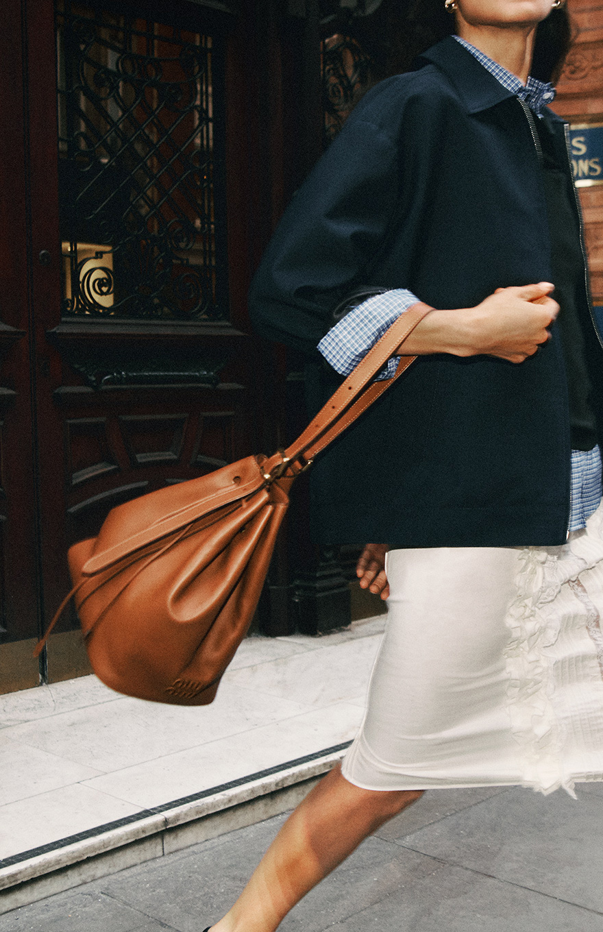 Woman in white skirt holding brown bag