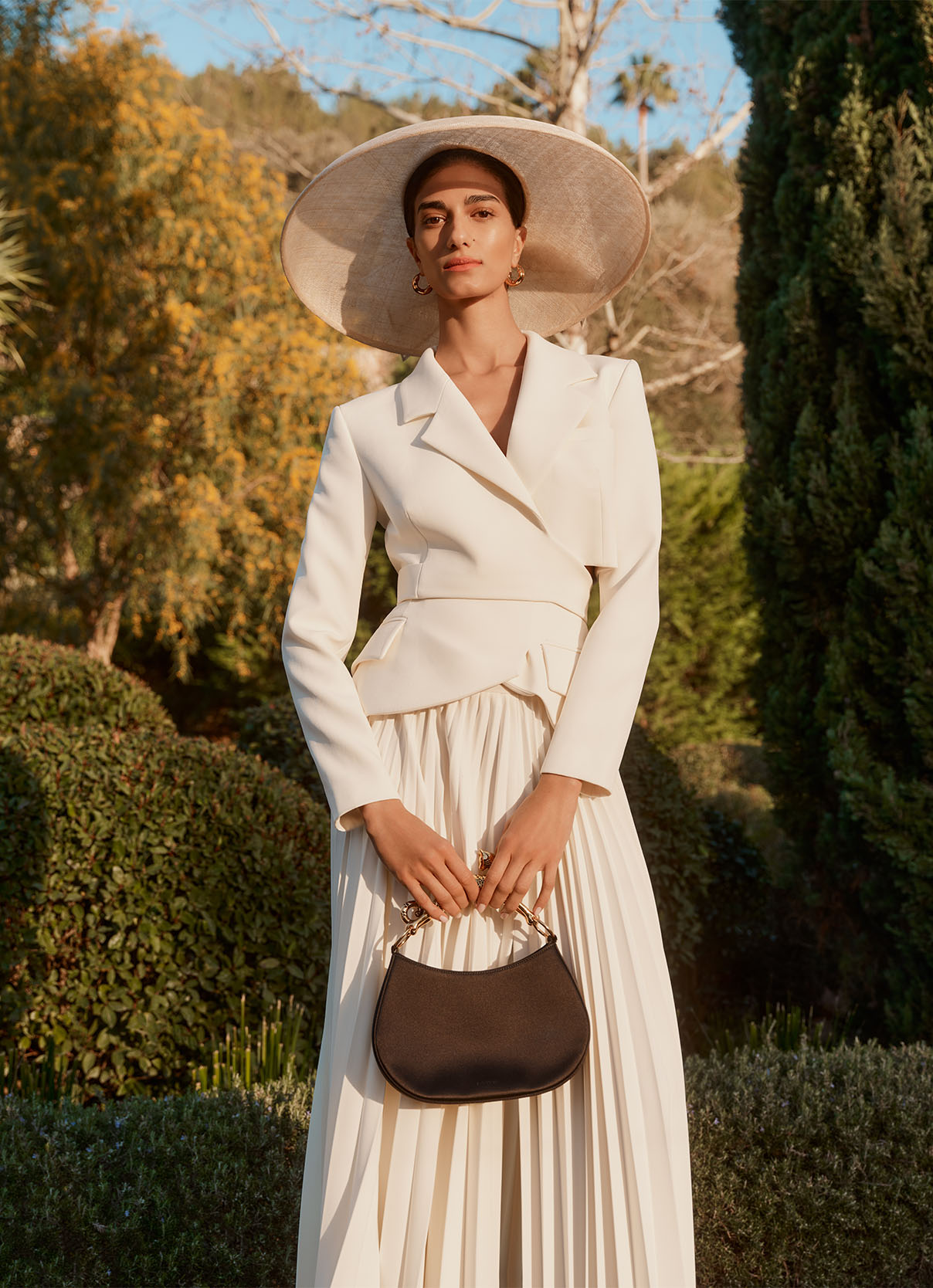 Model wears a cream A.W.A.K.E. Mode skirt suit and white Rachel Trevor-Morgan hat