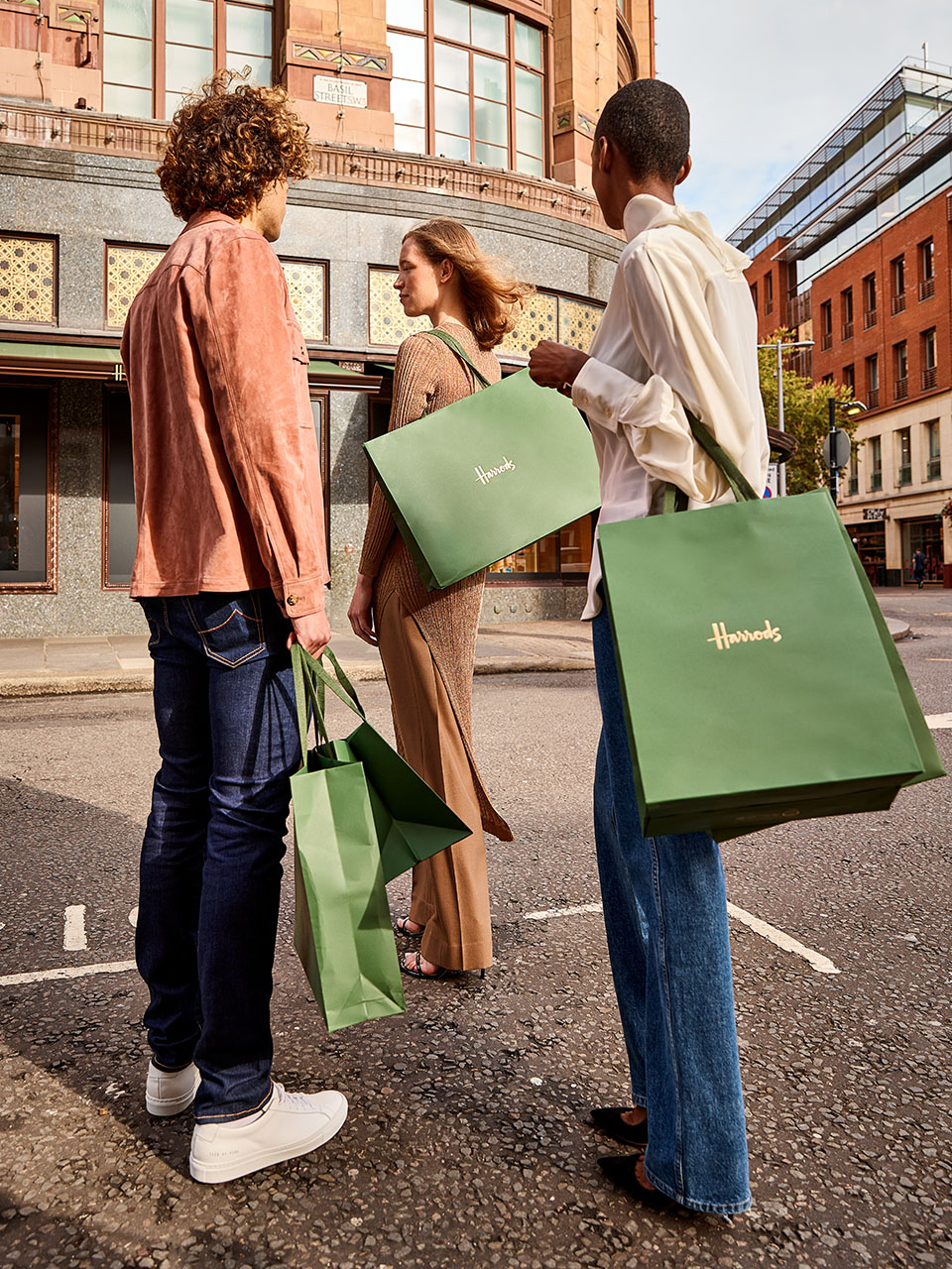 Group of friends outside Harrods holding the iconic Harrods green shopping bags