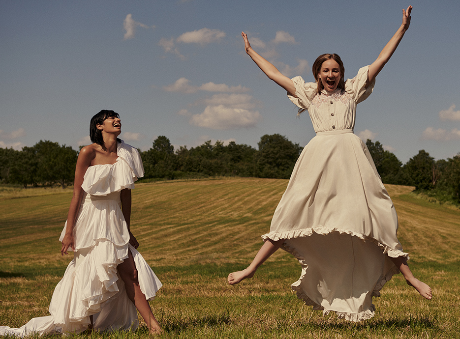 Rose & Ameera in white Alessandra Rich and Maticevski dresses jumping in the air