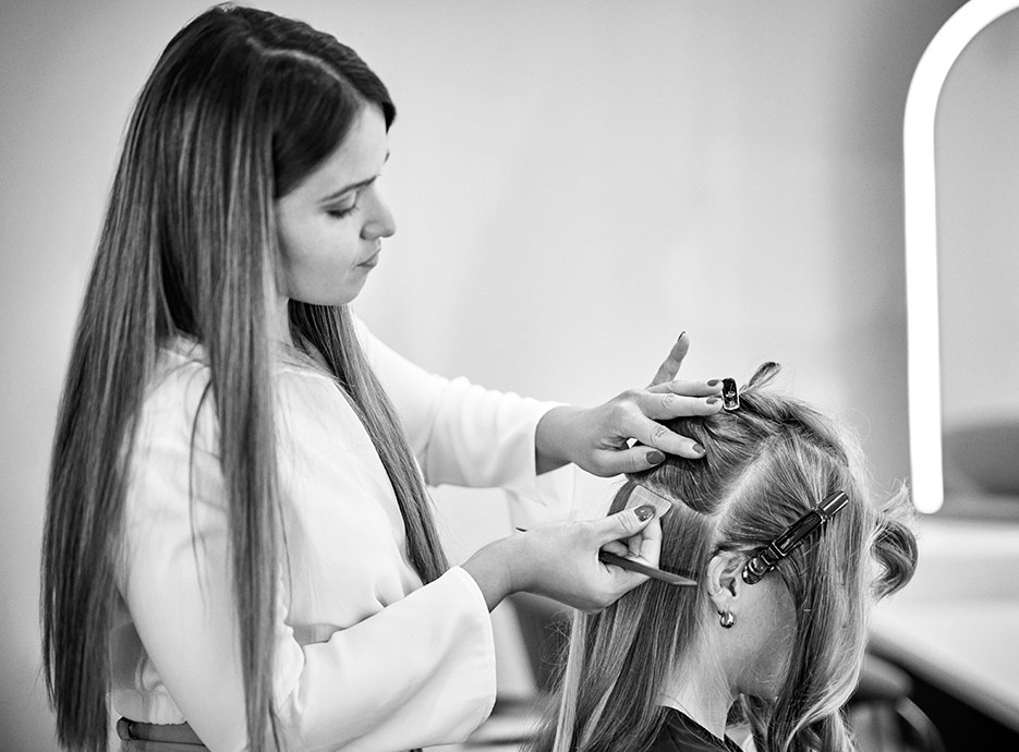 Woman having hair extension tapes added by stylist