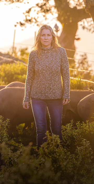 Woman from a sourcing farm, in the sun with pigs