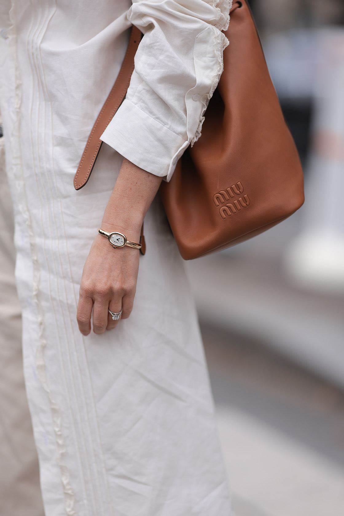 Woman wearing all white and a Cartier Baignoire watch with tan Miu Miu bag