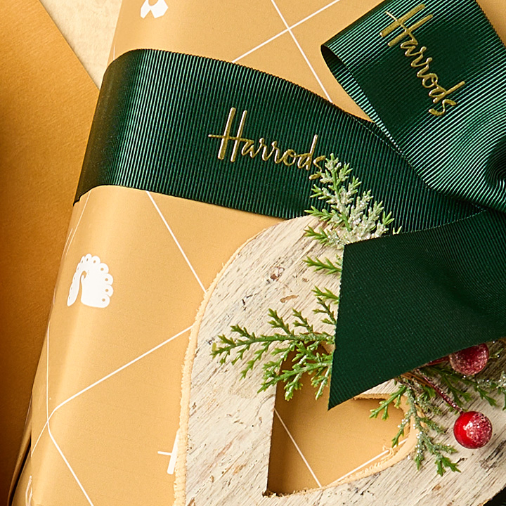 Golden wrapped gift with Harrods branded green ribbon